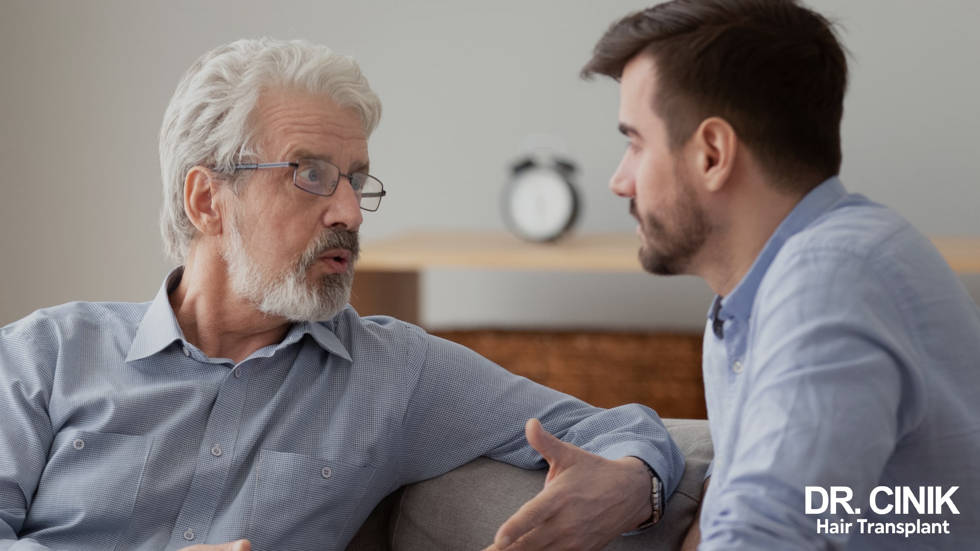 Un homme âgé à la barbe blanche discute avec un homme jeune à la barbe brune, illustrant l'évolution de la pilosité du visage au fil des décennies