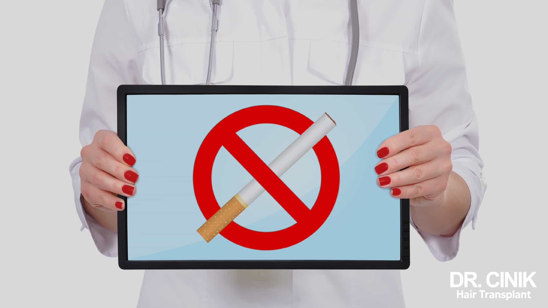 A healthcare professional in a white coat holds up a screen showing a red no-smoking pictogram