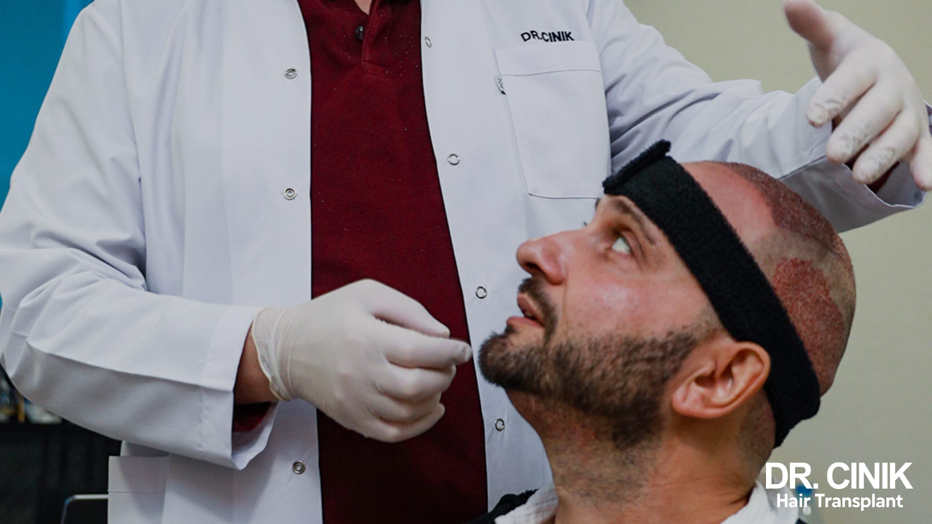A member of the medical team examines the recipient area of a patient wearing a black headband after his procedure