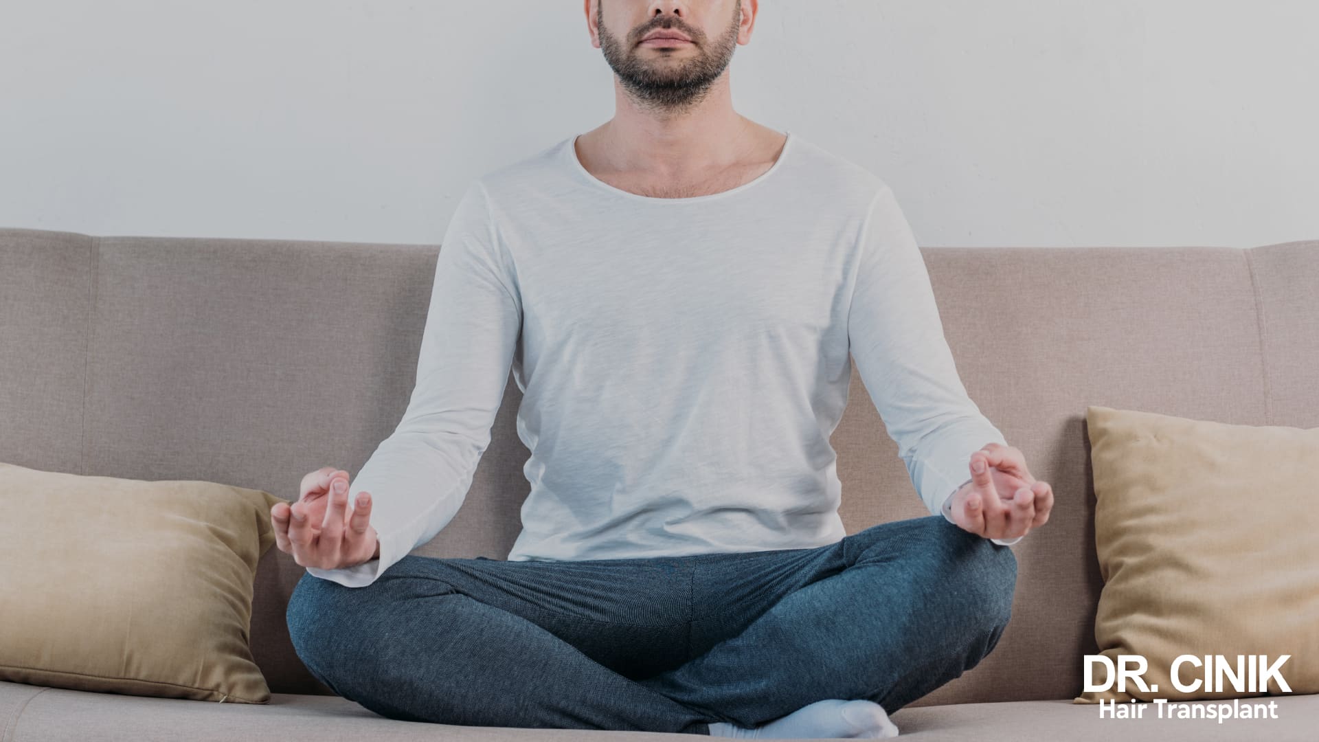 Man sitting cross-legged on a sofa, hands resting on his knees, in a relaxed posture before going to bed