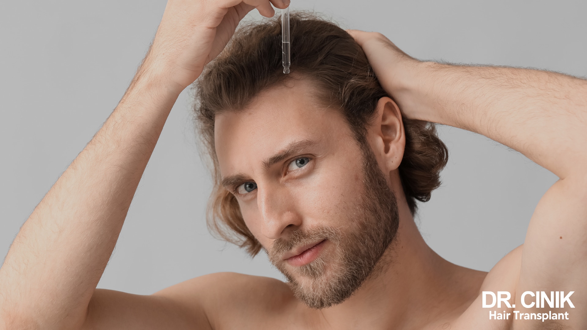 Man using a dropper to apply a hair product along the frontal hairline of his scalp