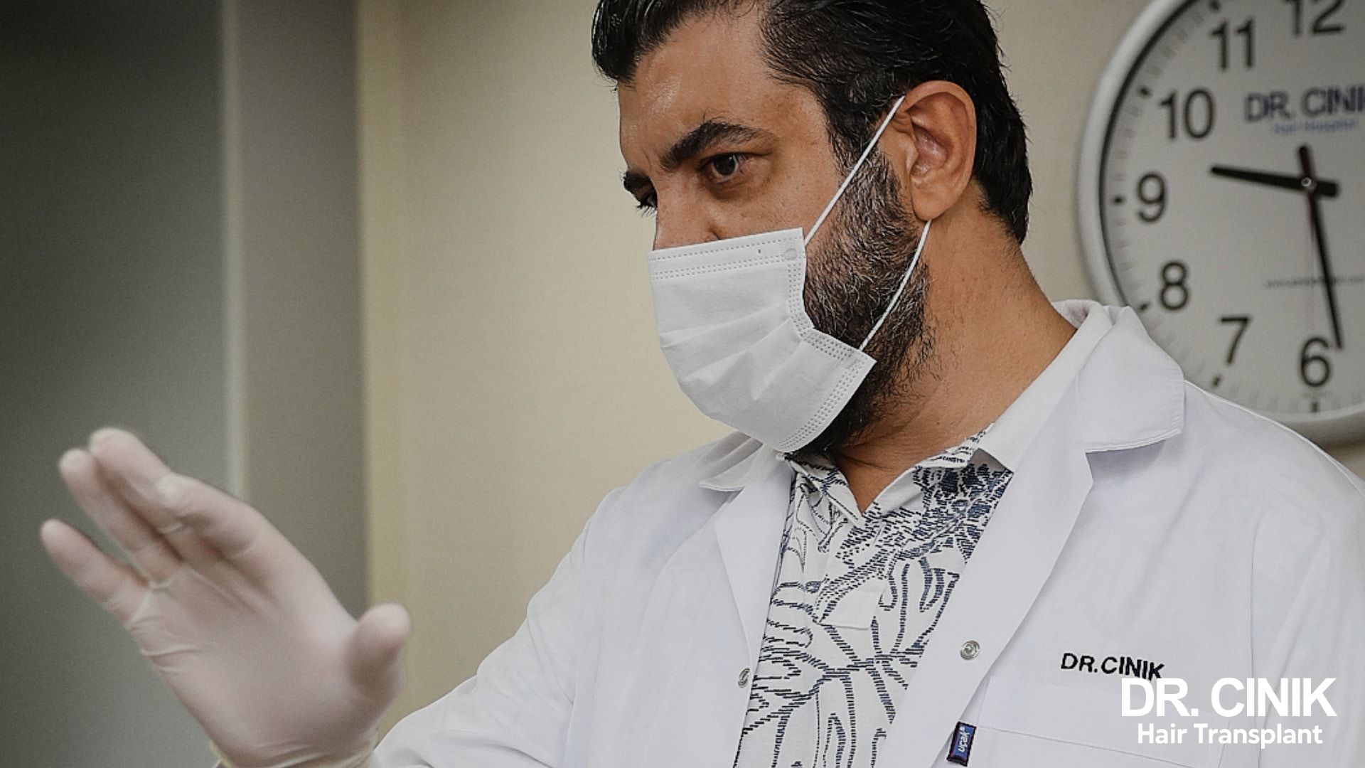 Doctor Emrah Cinik, masked and gloved, talks a patient through a post-operative instruction