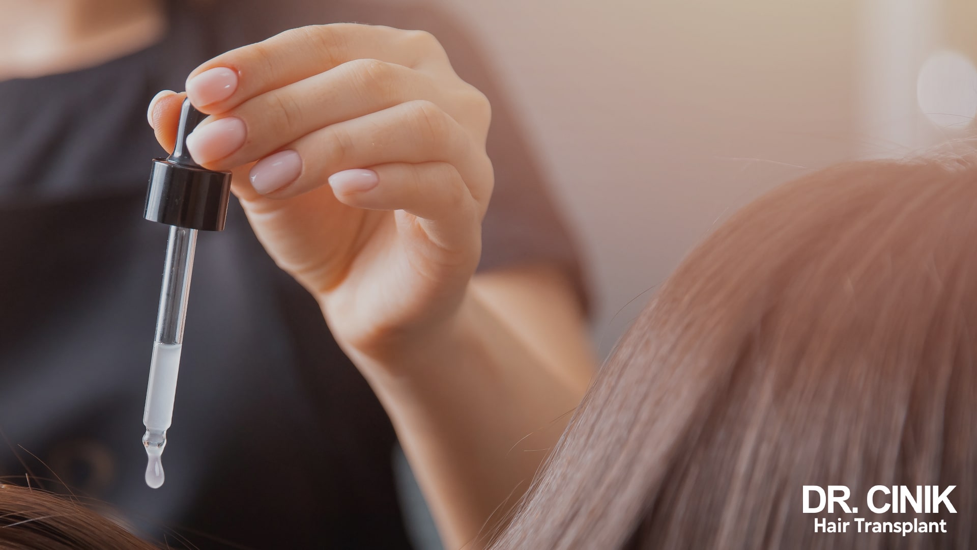 Woman's hand holding a pipette of hair treatment above dark brown hair