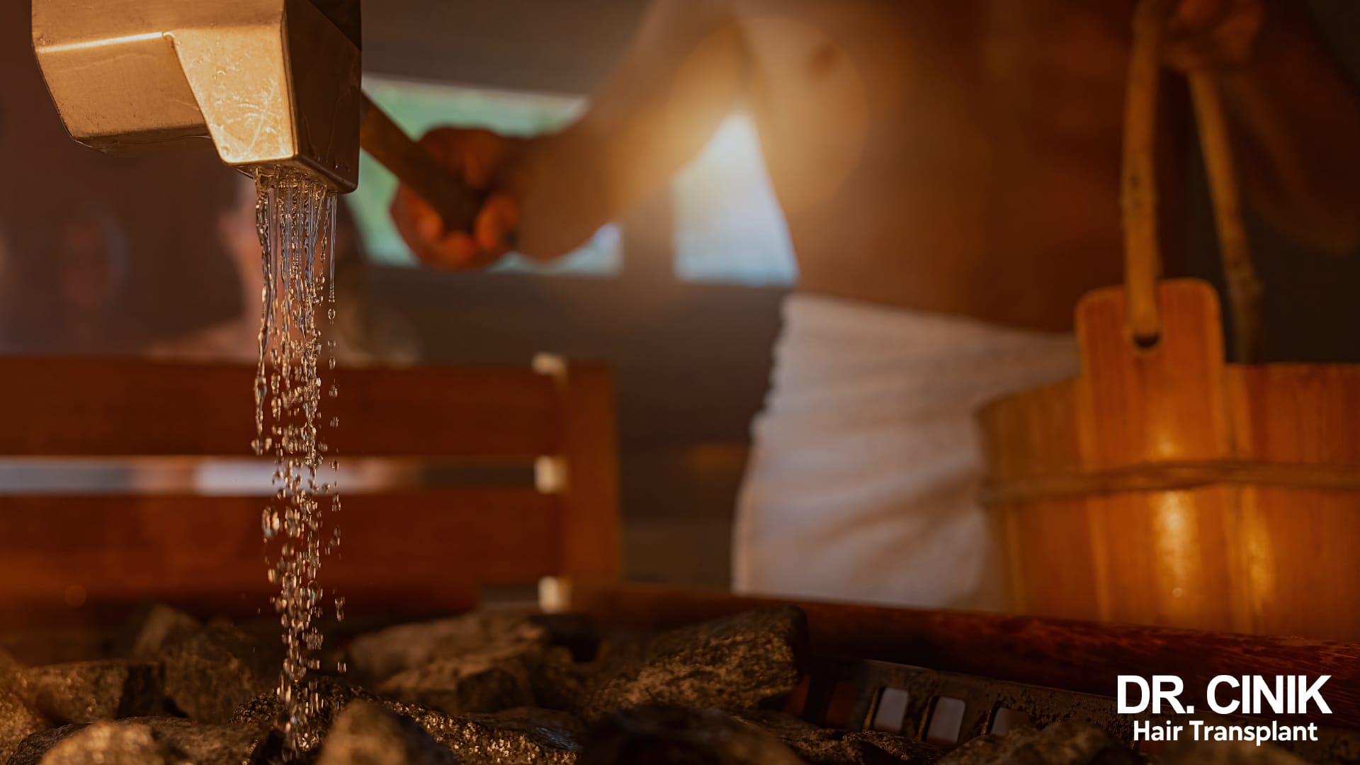 A wooden ladle pouring water over the hot stones of a sauna heater, in a timber cabin