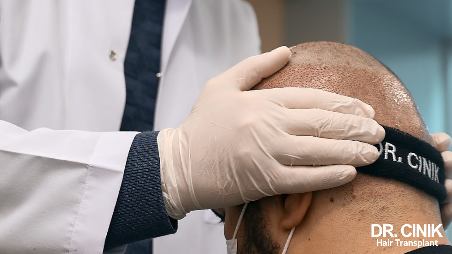 Gloved practitioner examining the implanted scalp of a patient wearing a post-operative clinic headband