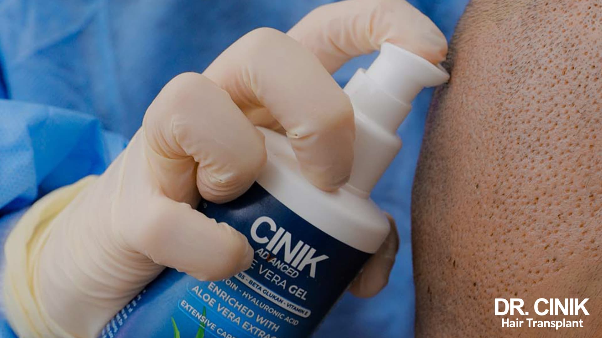 Gloved hand applying a soothing Dr Cinik gel to the shaved donor area, the extraction points still visible on the skin