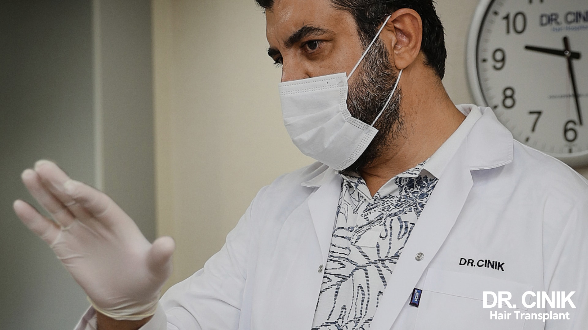 Doctor Emrah Cinik, in surgical mask and glove, explains an instruction to a patient in his consulting room