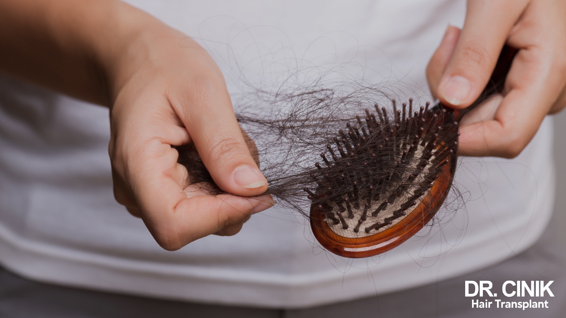 Hand holding a hairbrush loaded with a mass of shed hair