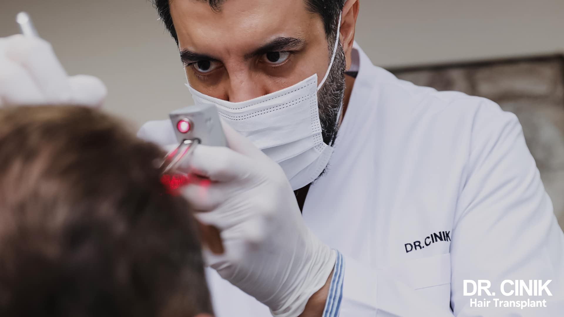 Dr Cinik in a white coat examining a patient's scalp with a handheld analysis device