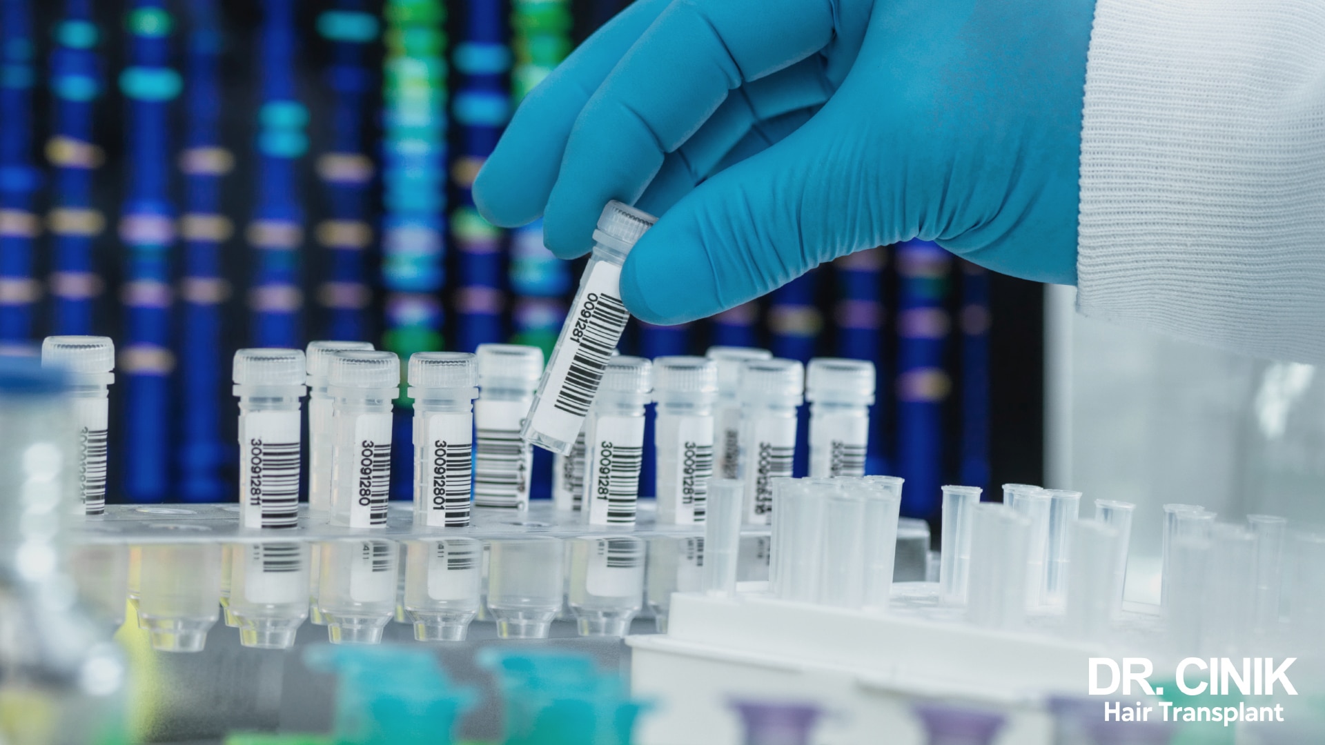 Gloved hand holding a barcoded sample tube in front of a DNA sequencing profile in a laboratory