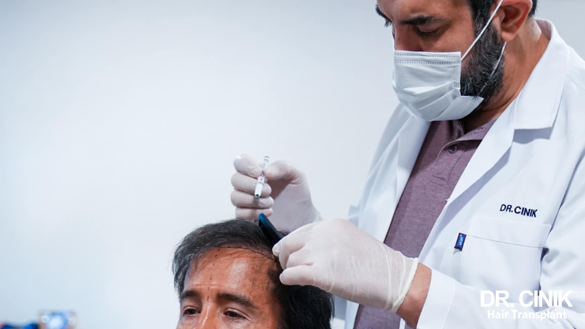 Dr Cinik preparing a local anaesthetic on the head of a seated patient