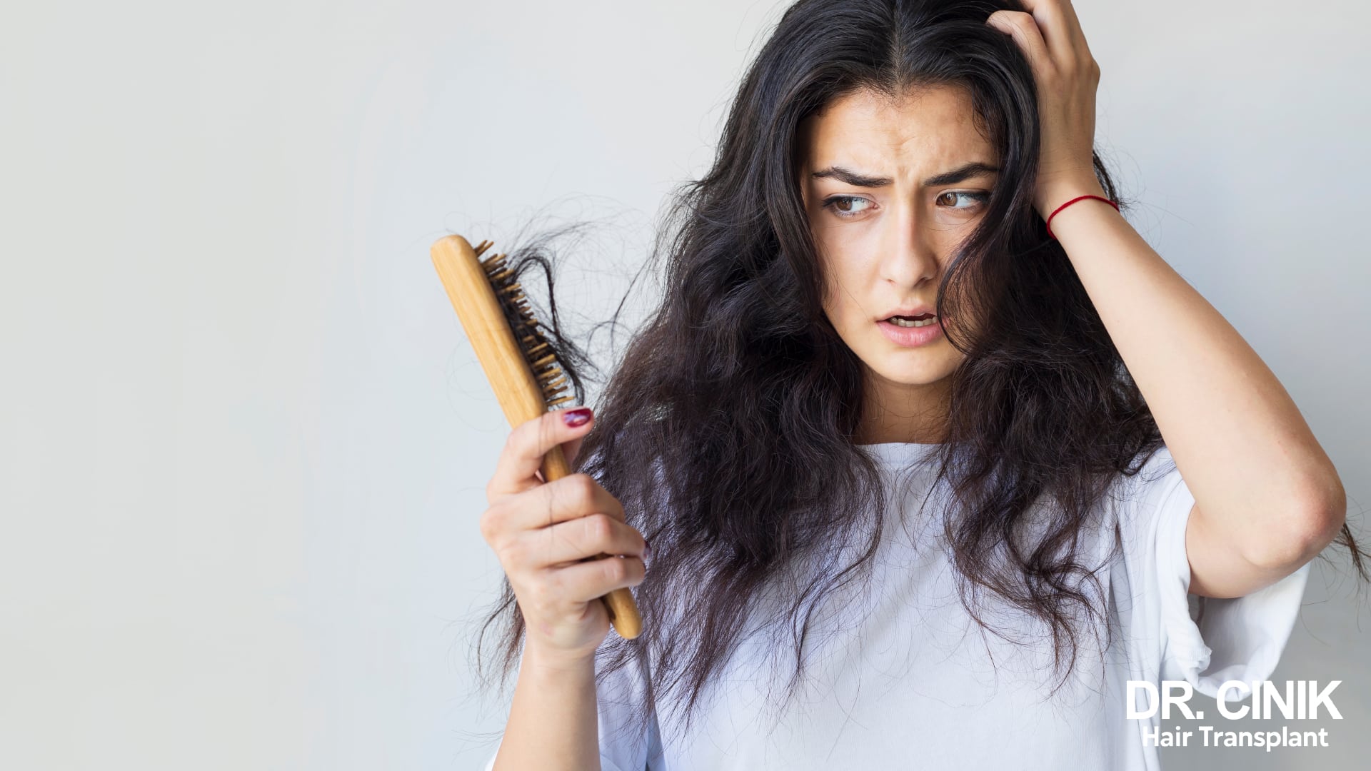 Woman looking at her hairbrush loaded with shed hair