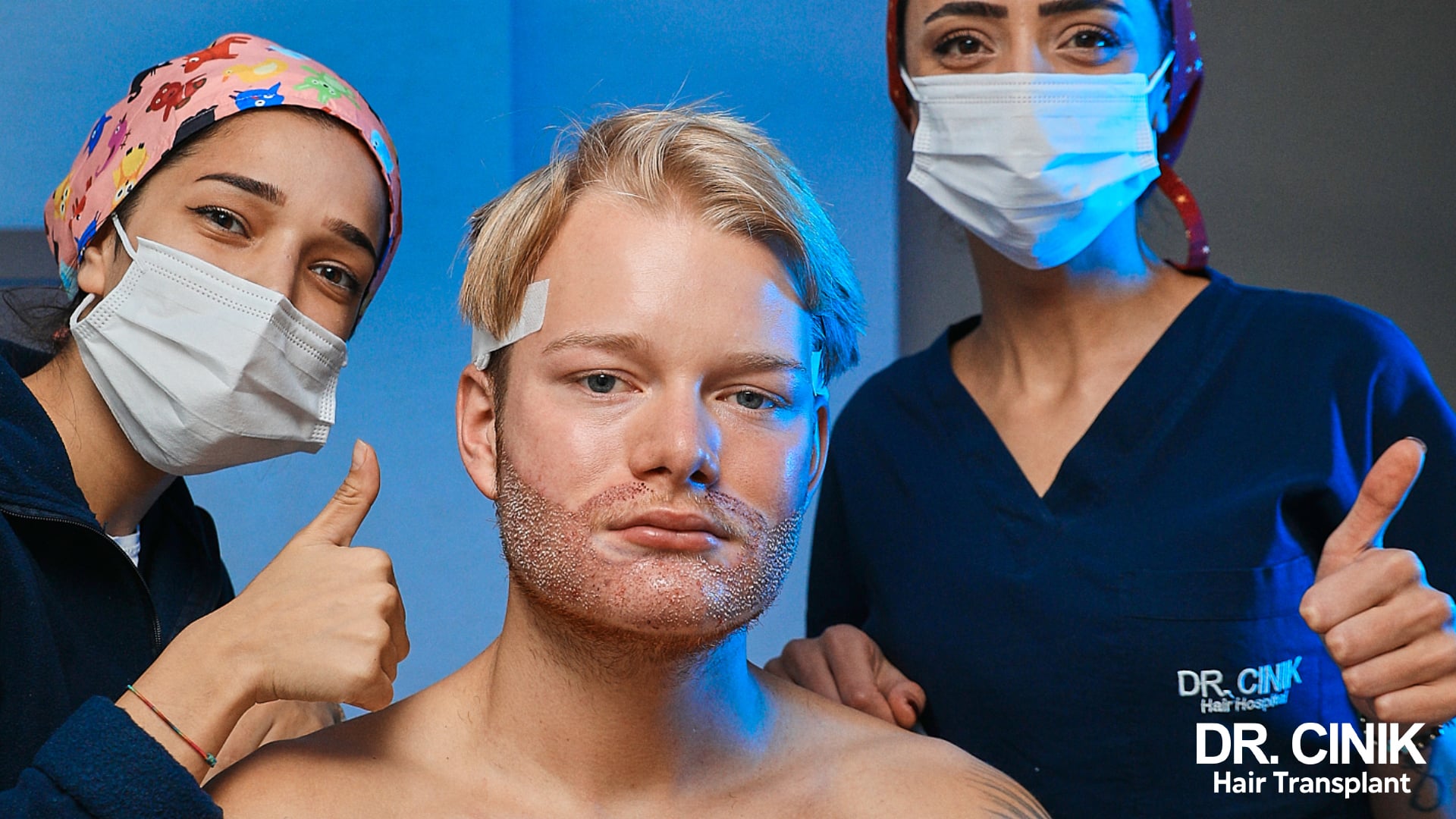 Un patient entouré de deux infirmières de la clinique après sa greffe de barbe, les zones implantées encore recouvertes de croûtes fines