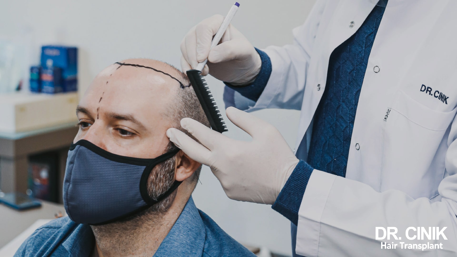 Dr Cinik drawing the future hairline on a patient's scalp with a marker pen, comb in hand