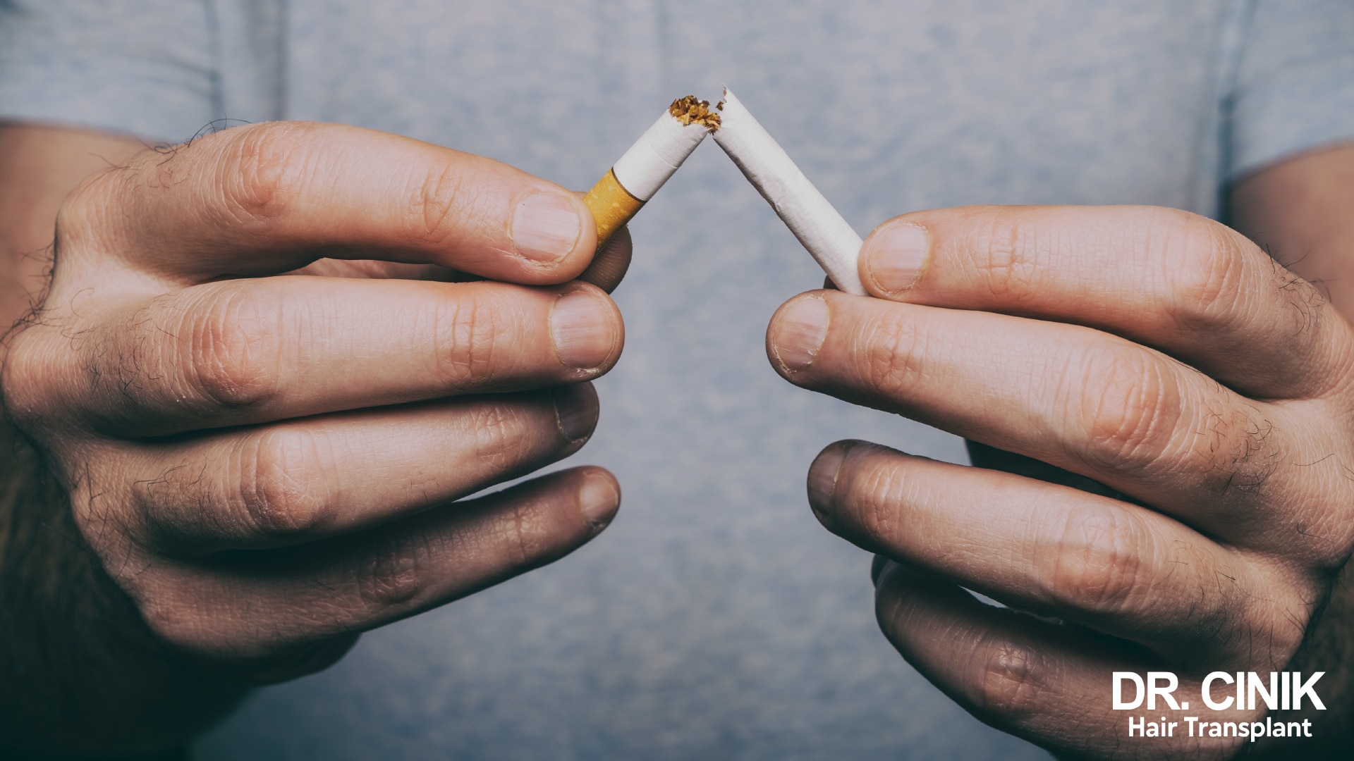 Two male hands snapping a cigarette in half