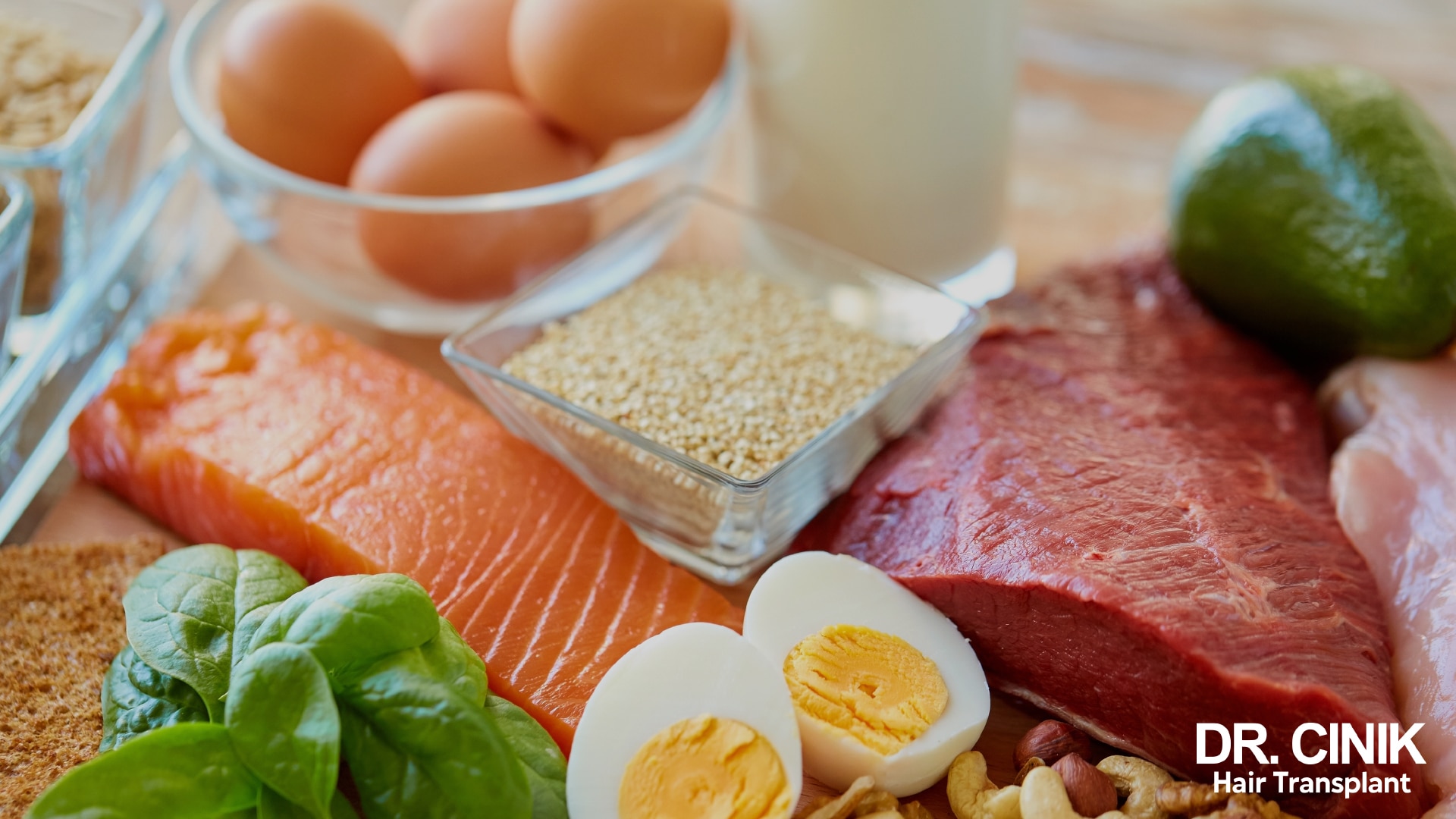 Assortment of protein and nutrient-rich foods: whole and halved eggs, raw salmon, red meat, spinach, walnuts, sesame, avocado and milk