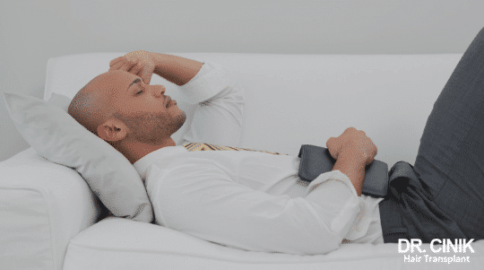 Patient lying on his back, head resting on a pillow and slightly raised, in the sleeping position recommended after a hair transplant
